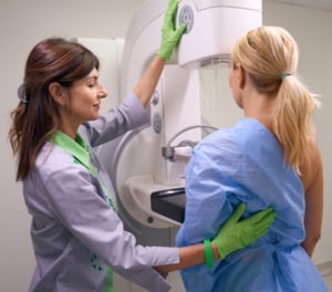 Radiologa aiuta paziente a posizionarsi per effettuare la mammografia